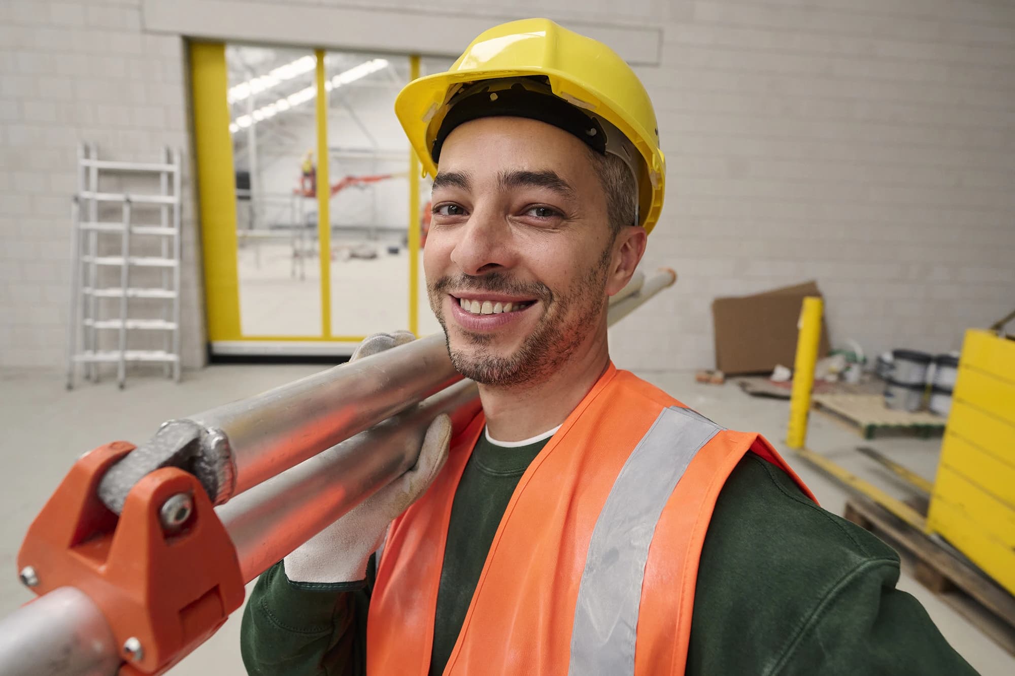 Muncitor în construcții cu cască și vestă reflectorizantă zâmbește pe șantier — locuri de muncă în construcții prin Accent